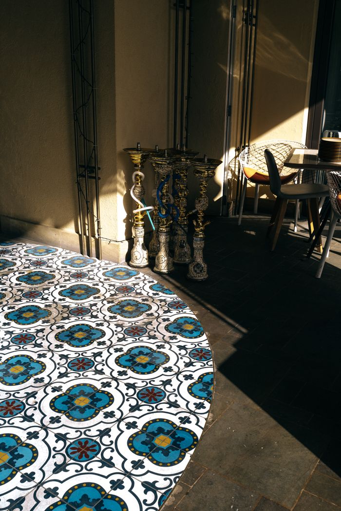 A sunlit porch featuring ornate shishas and colorful mosaic tiles, embodying Middle Eastern charm.